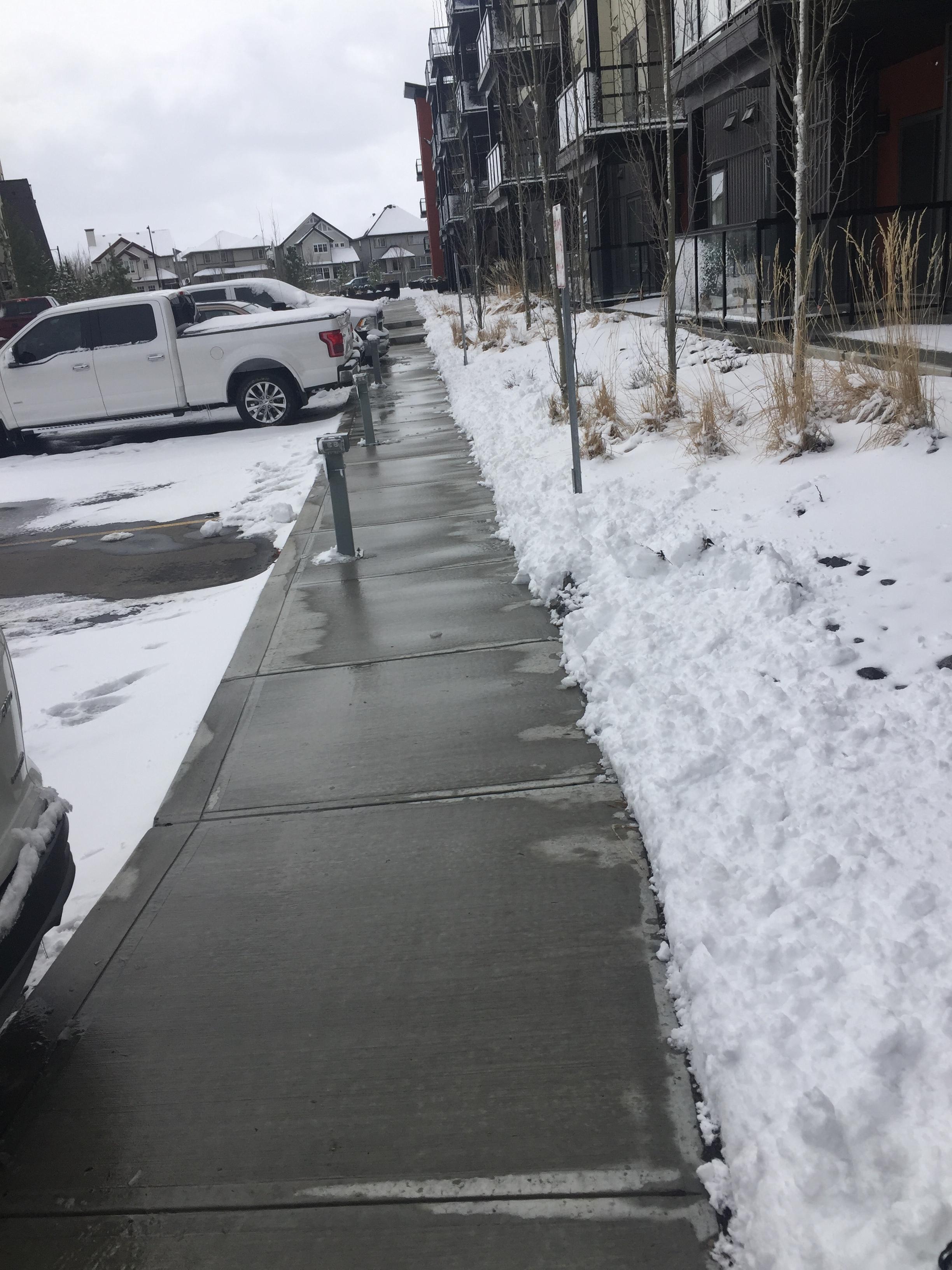 Commercial sidewalk cleared beside apartment building with snow banks